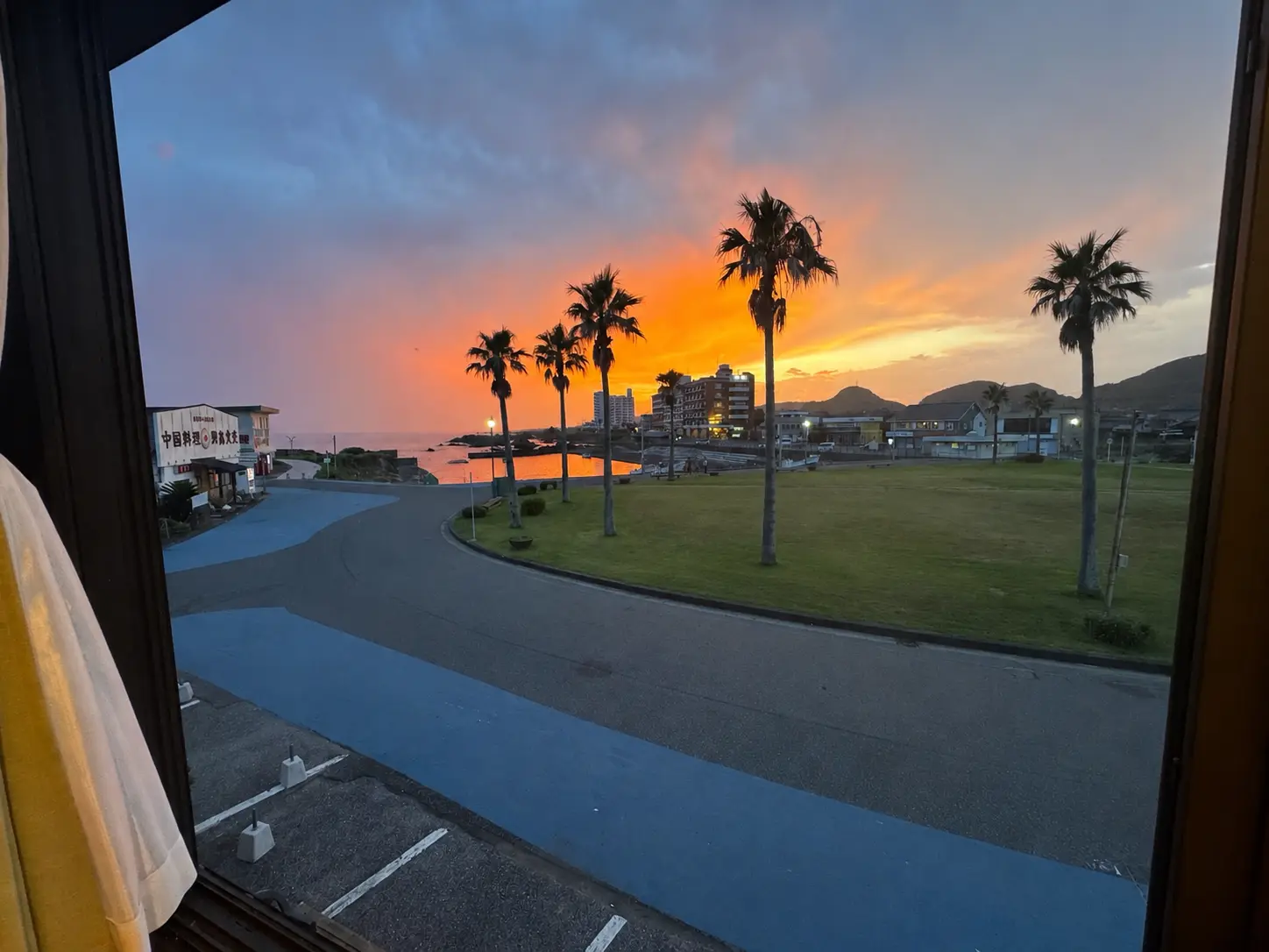 大きな窓から白浜の港と夕焼けが見える、白燈の海側客室